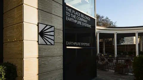 A dark Earthpure Systems sign with a sunburst mark on a building wall.