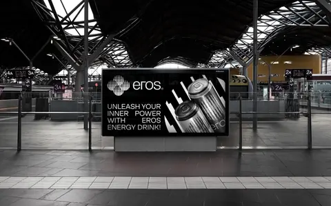 An energy drink advert on a screen in a train station.