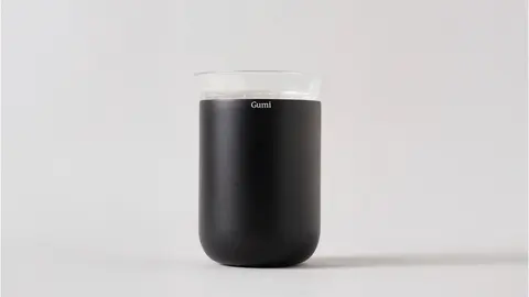 A matte black Gumi jar on a pale ground.