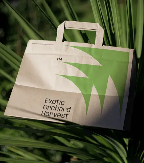 Kraft paper bag with a green mark among palm leaves.