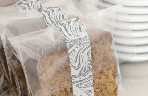Pastries wrapped in clear film with a black and white marbled paper band.