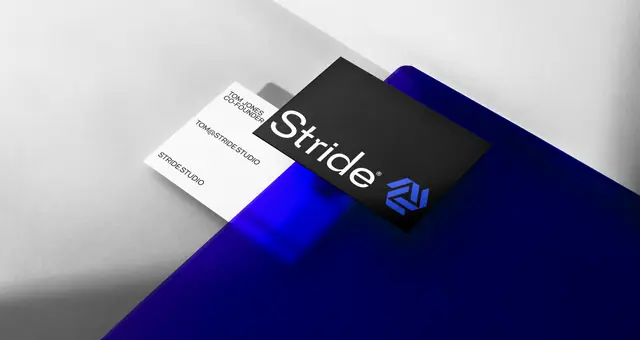 Black and white Stride business cards lie on a white surface with a bright blue fold.