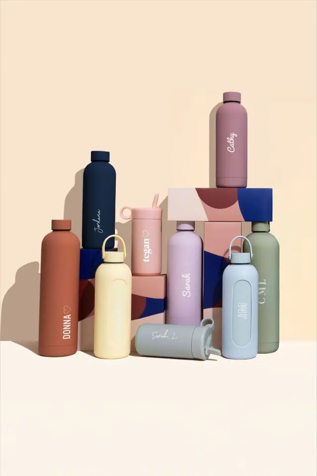 Pastel drink bottles with handwritten names, grouped on blocks on a cream ground.