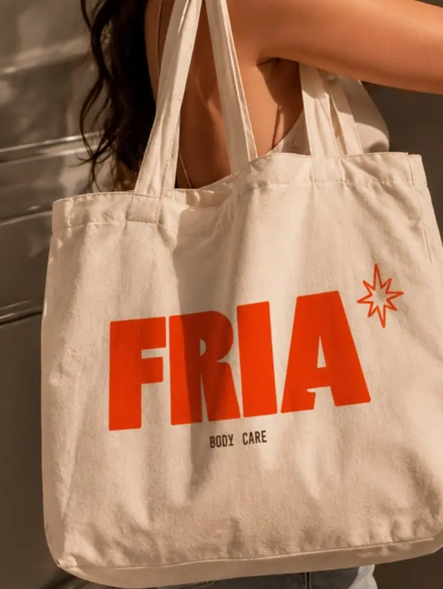 A canvas tote bag with a large red wordmark and star, carried on a shoulder.