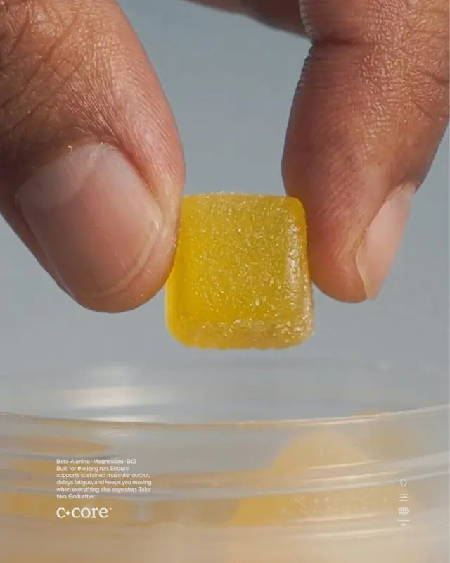 Fingers holding a yellow gummy above an open jar, with small product notes.