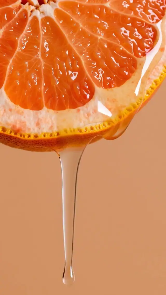 Juice drips slowly from a grapefruit slice on a peach ground.